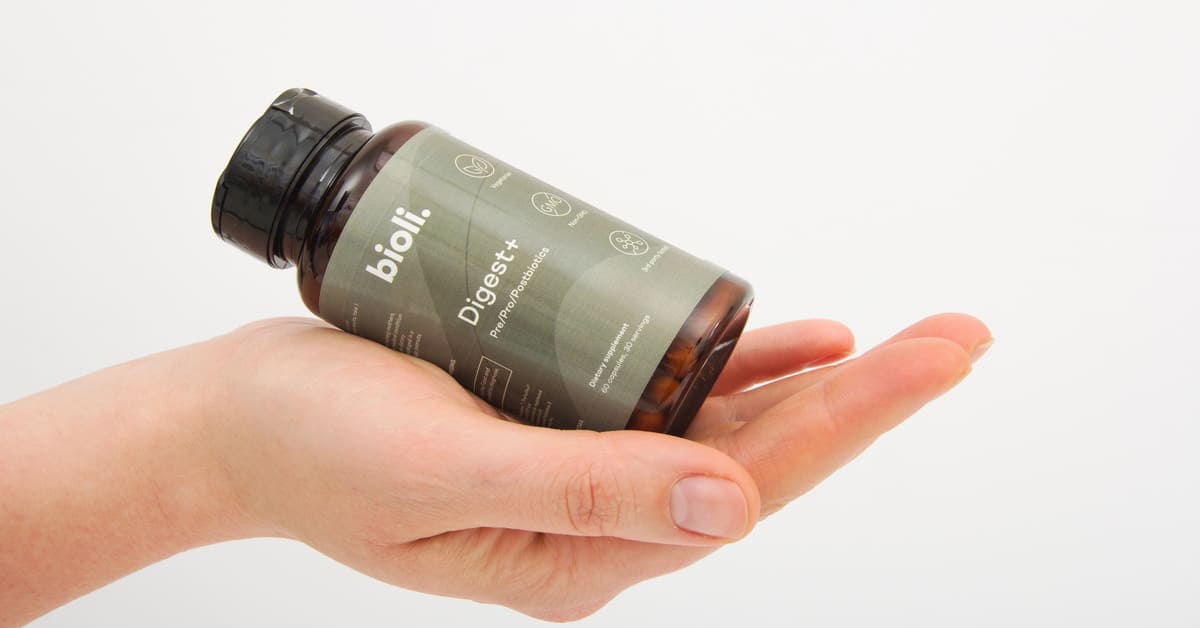 Hand holding two white Bioli capsules.